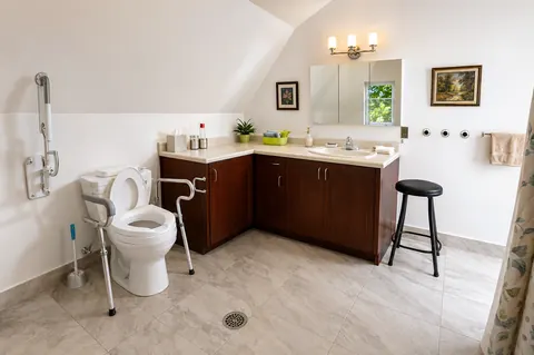 Salle de bain adaptée avec barres d'appui et chaise de douche